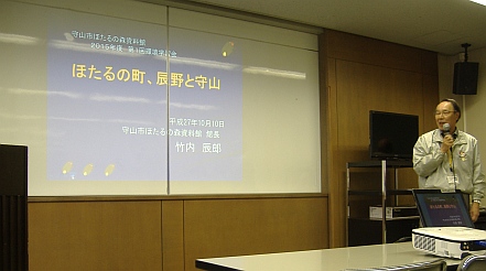 ほたるの森資料館館長，竹内辰朗氏が，ほたるの町 辰野と守山の関係を紹介する様子。